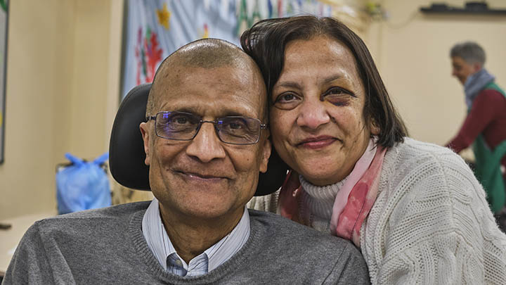 Close-up of a smiling elderly couple embracing warmly indoors.